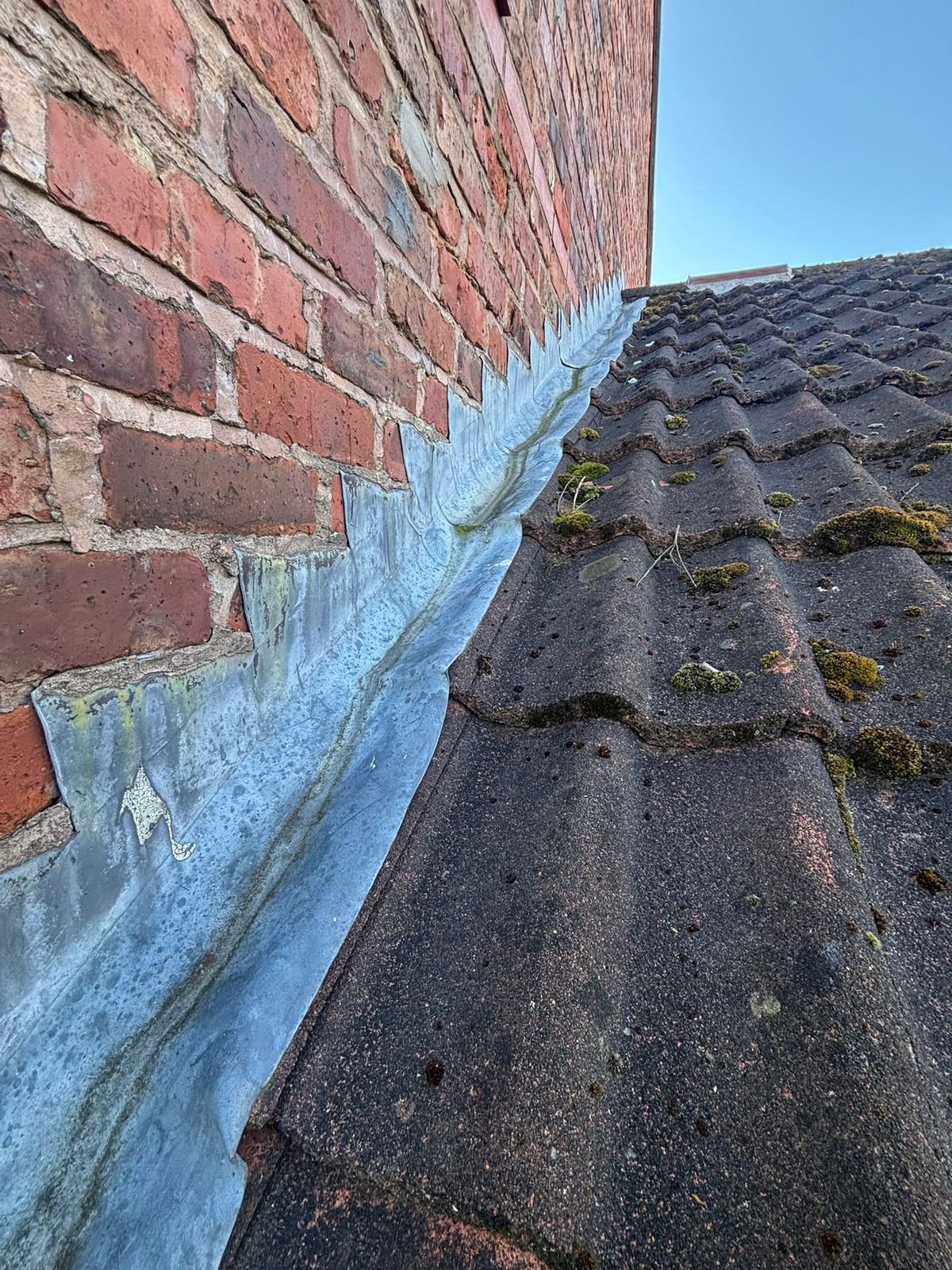 Old perished lead flashing against a brick wall before the job